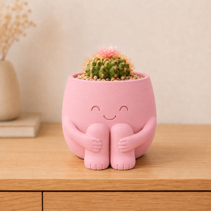 Vaso amiguinho sentado abraçando os joelhos, com carinha de olhos fechados, na cor rosa