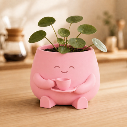 Vaso amiguinho segurando uma xícara com as duas mãos, com planta no topo