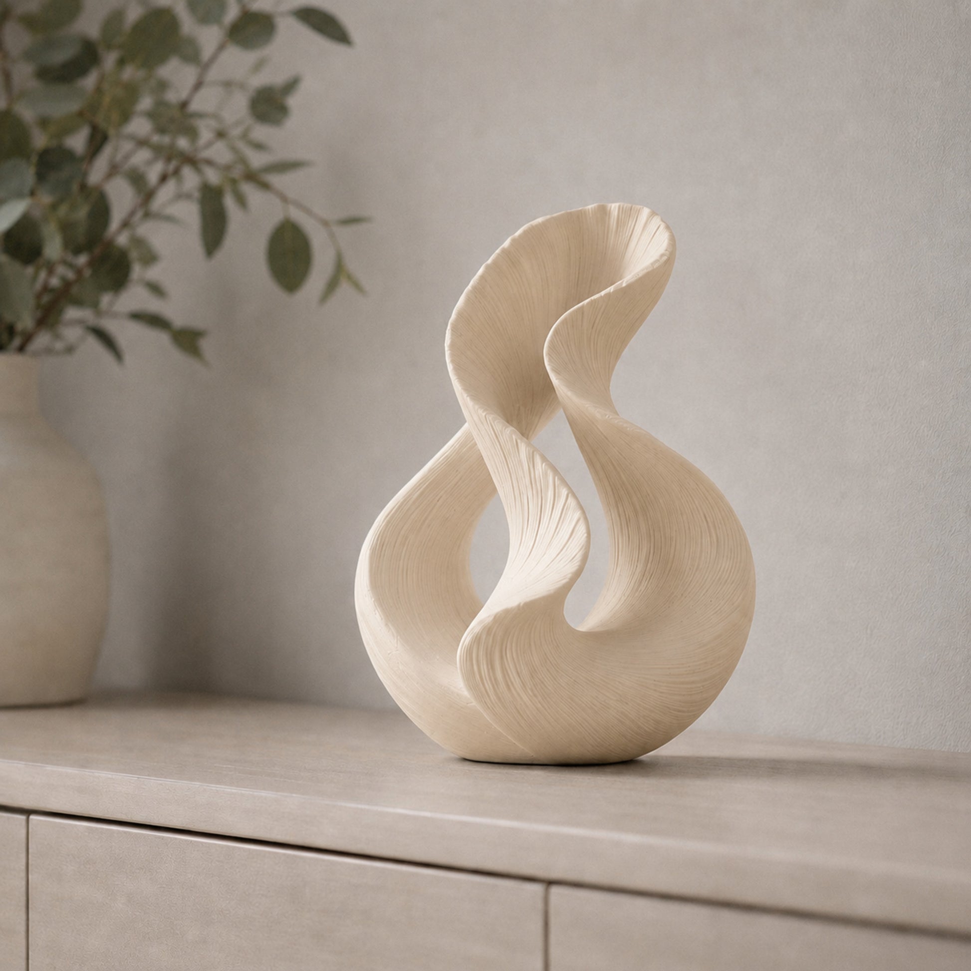 Escultura decorativa com duas curvas entrelaçadas, na cor bege