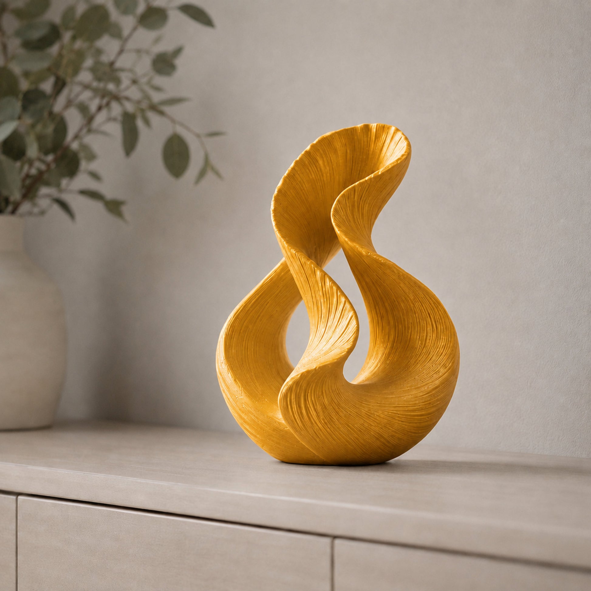 Escultura decorativa com duas curvas entrelaçadas, na cor dourada