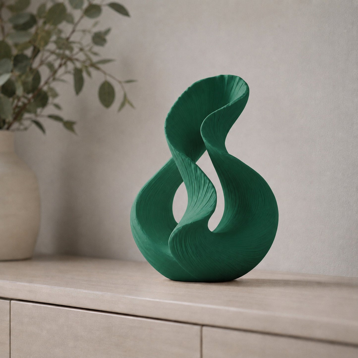 Escultura decorativa com duas curvas entrelaçadas, na cor verde escura