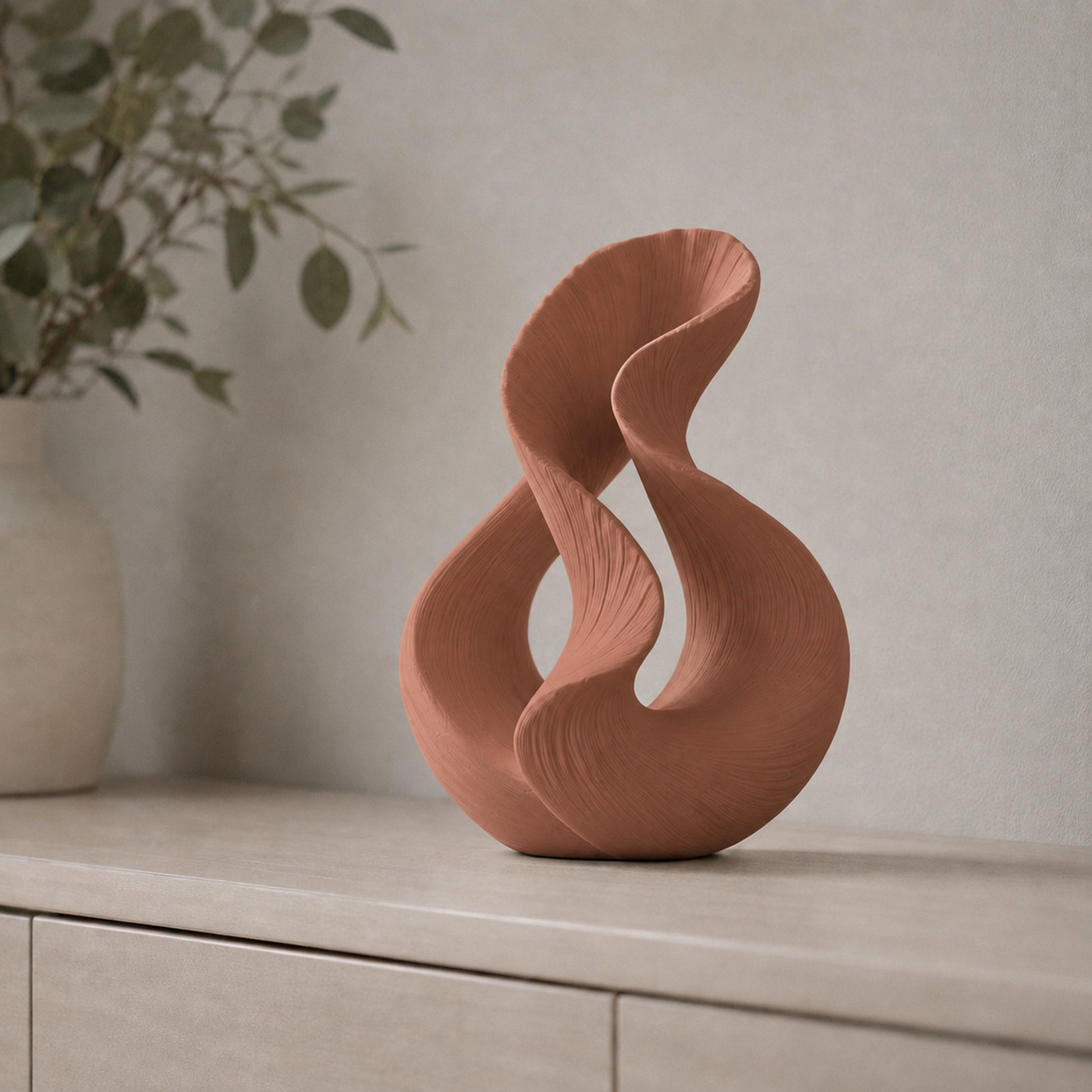 Escultura decorativa com duas curvas entrelaçadas, na cor marrom terracota